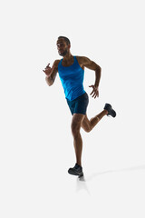 Front view vertical image of concentrated man, runner with muscular strong body in motion, running isolated on white background. Concept of sport, competition, endurance, athletics, sportive lifestyle