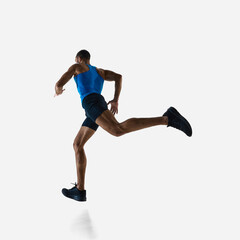 Low angle side view of muscular man, runner in motion, running, training isolated on white studio background. Concept of sport, competition, endurance, athletics, sportive lifestyle.