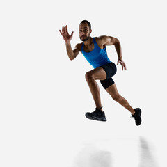 Fototapeta premium Focused man, runner athlete with muscular body in motion, training isolated on white studio background. Concept of sport, competition, endurance, athletics, sportive lifestyle. Copy space