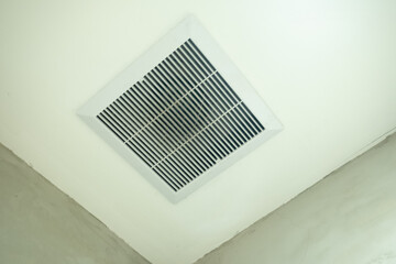A white exhaust fan mounted on the ceiling, designed for ventilation and air circulation in an...