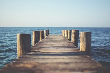 Obraz premium Wooden pier extending into calm waters under a clear blue sky during a serene morning. Generative AI