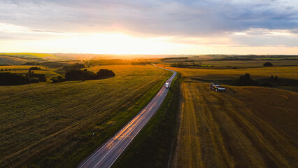 The car is driving along the highway at dawn
