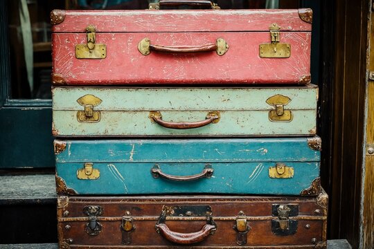 Cuatro maletas vintage apiladas, cada una con un color y textura distintiva, evocando recuerdos de viajes pasados.
