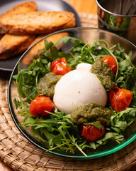 Fresh Italian burrata salad with pesto, cherry tomatoes and arugula