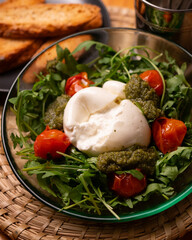 Fresh Italian burrata salad with pesto, cherry tomatoes and arugula