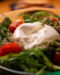 Fresh Italian burrata salad with pesto, cherry tomatoes and arugula