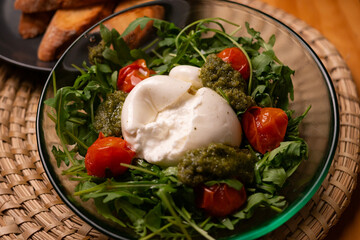 Fresh Italian burrata salad with pesto, cherry tomatoes and arugula