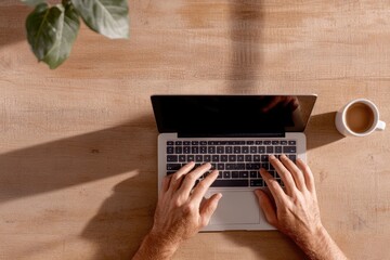 stock photo of online class in progress hands typing on laptop keyboard coffee cup nearby neat and cozy home office