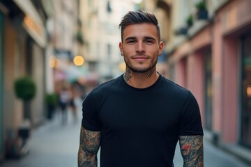 Fototapeta premium Smiling young man with tattoos standing in an urban street setting with blurred background