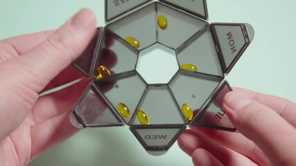 Rotating transparent pill organizer, revealing yellow capsules sorted in labeled daily compartments with weekday abbreviations