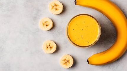 Banana smoothie poured in glass with slices on marble; health food concept