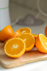 Fresh orange halves arranged on a rustic wooden surface in a kitchen setting, ready for juicing. Natural light enhances their vibrant color and juicy texture.