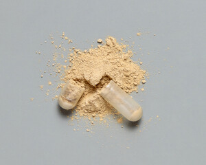 Opened Medical capsule to show beige powder on grey top view. Alternative dietary supplements