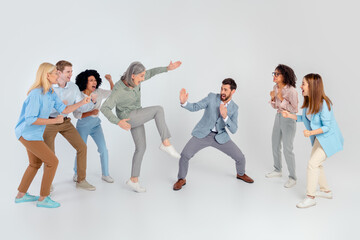 Diverse team in a dynamic office moment expressing creativity and teamwork against a grey background