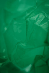 Obraz premium Extreme close up of green empty plastic bag background. The plastic surface is wrinkly and tattered making abstract pattern. Selective focus, shallow depth of field.