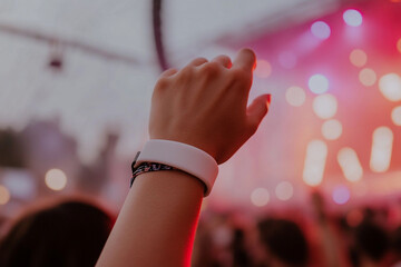 Hand with wristband raised at outdoor music festival concert. Silicone bracelet, paper wristband mockup