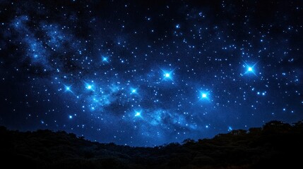 Starry night sky above a dark silhouette of trees.