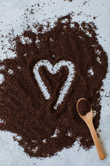 Heart drawn in ground coffee spilled on surface with wooden spoon. Overhead top shot. Concept of love and coffee