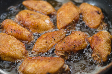 Crispy fried chicken wings in a frying pan