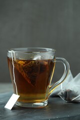 Tea bag in glass cup with hot drink on gray table