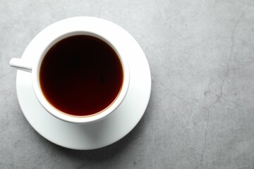 Refreshing black tea in cup on grey textured table, top view. Space for text