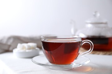 Refreshing black tea in cup on light table. Space for text