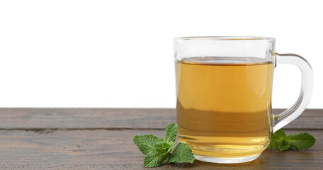 Aromatic mint tea in glass cup and fresh leaves on wooden table against white background, space for text