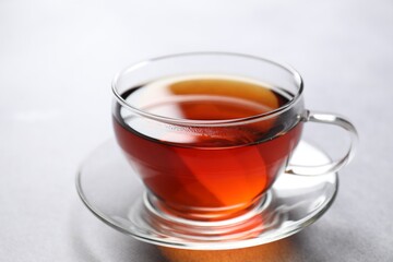Aromatic black tea in cup on light table, closeup