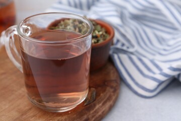 Delicious herbal tea and dry leaves on white table, closeup. Space for text