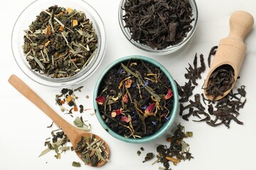 Fototapeta premium Different dry tea leaves on white table, flat lay