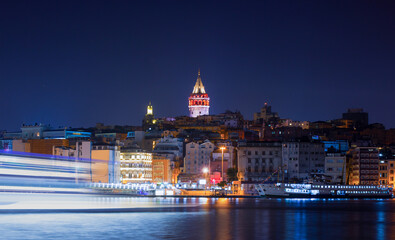 Obraz premium Galata Tower, Galata Bridge, Karakoy district and Golden Horn with motion speed light of passing ferry in the foreground at night istanbul - Turkey 