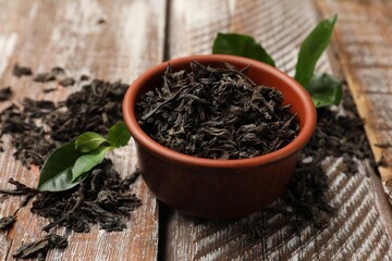 Dried and fresh tea leaves on wooden table, closeup