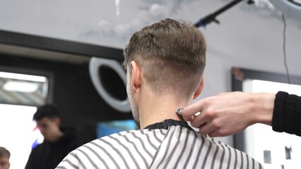 Skilled barber trimming client's neck hairline, wielding straight razor with expertise in...