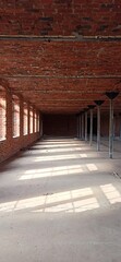 An abandoned brick building with metal columns and windows letting in sunlight. The atmosphere of the industrial past, a space for artistic photography and urban exploration.
