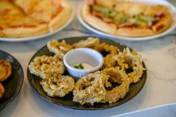 Fried onion rings on a serving plate on the table with other food