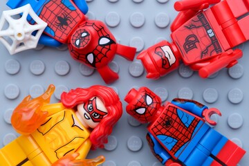 Naklejka premium Tambov, Russian Federation - February 03, 2025 Four Lego Marvel character minifigures - Spider-Ham, Daredevil, Firestar and Spider-Man, on gray baseplate background.