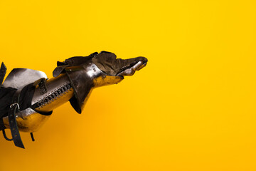 Closeup of an armored hand against a bright yellow background symbolizing history and valor