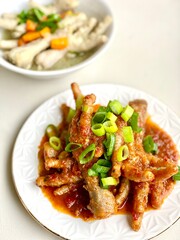 Chicken feet with spicy chili sauce or ceker mercon on a serving clay plate and white napkin. ceker pedas. ceker mercon jualan