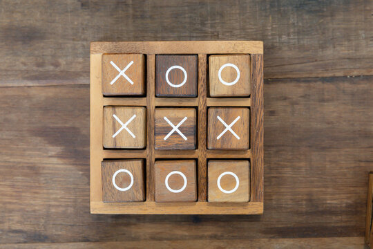 A wooden board with the letters X and O on it. tic tac toe wooden game on timber table.