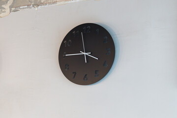 A black steel clock with white hands showing the time of 15:45, in the afternoon time.