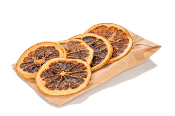 Several slices of dried grapefruit, close-up, on a paper bag, isolated on a white background.