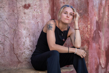 A beautiful woman sitting by an old pink wall