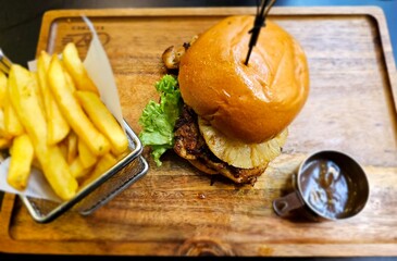 Hamburger with pineapple and chips at the side.