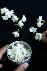 Jasmine flowers in silverware glass with black background. Close-up white jasmine floating water in small glass that makes the water smell good. White flower, freshness, decor, and scent concepts.