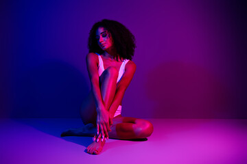 Young woman posing in colorful lighting, showcasing beauty and confidence