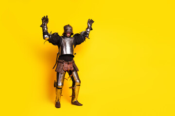Funny medieval knight in armor posing against vibrant yellow background with enthusiastic gestures