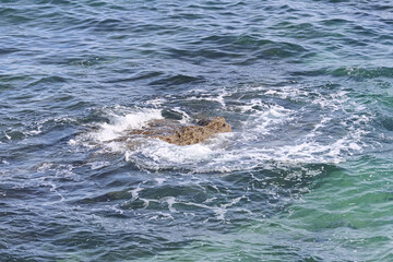 Rocks on the shore between the waves.