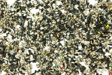A chaotic assortment of various screws, bolts, and fasteners in mixed metallic and black tones, scattered randomly on a white background