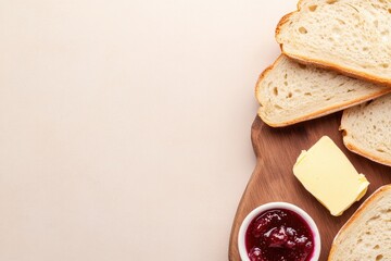 Freshly sliced bread arranged on wooden board with butter and ja