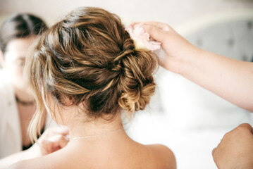 Naklejka premium Elegant bridal hairstyle with a romantic, tousled updo adorned with a soft pink flower. The natural, textured look and gentle tones create a dreamy and timeless wedding vibe.